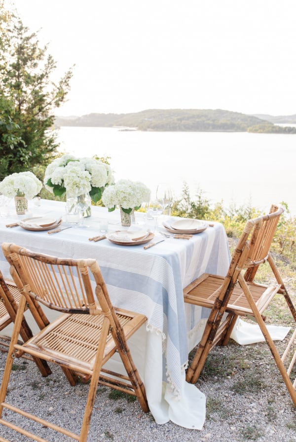 A blue and white table cloth set with bamboo plates and an al fresco dining view.