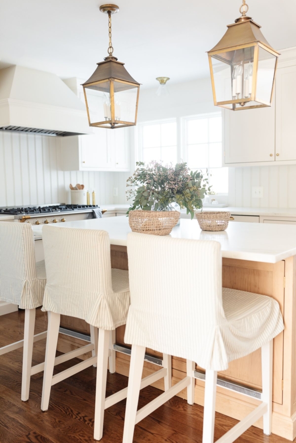 Kitchen island bar stools with striped slipcovers in a white kitchen