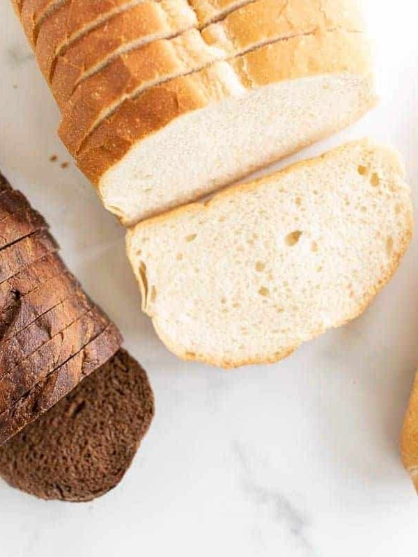 Three different loaves of bread on a marble surface, in a post about the best bread for grilled cheese.