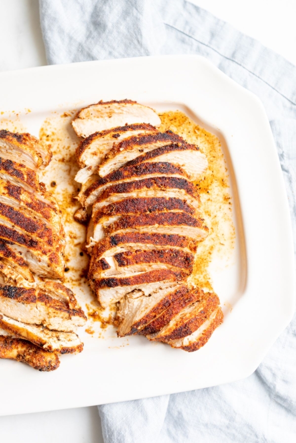 Sliced blackened chicken on a white serving platter.