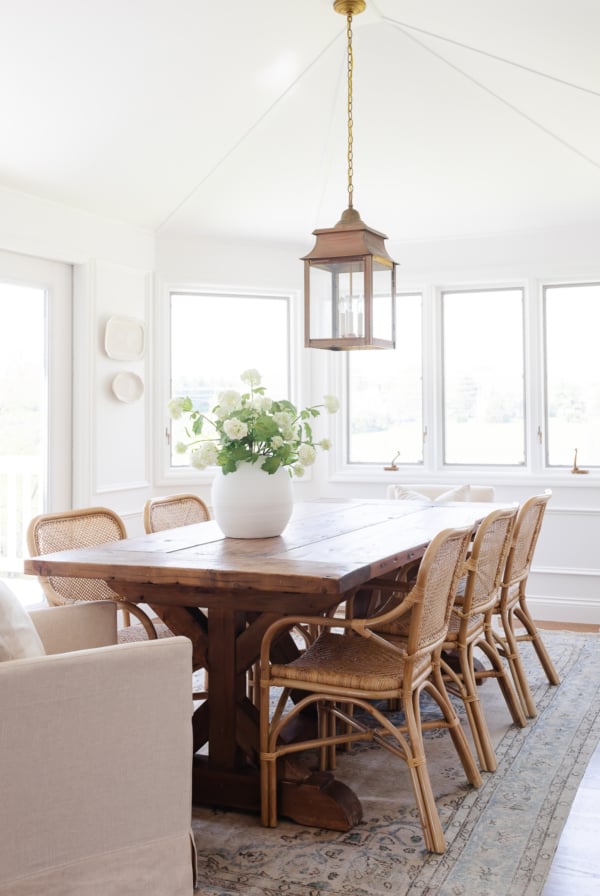 A white windowed breakfast nook with a wood dining table.