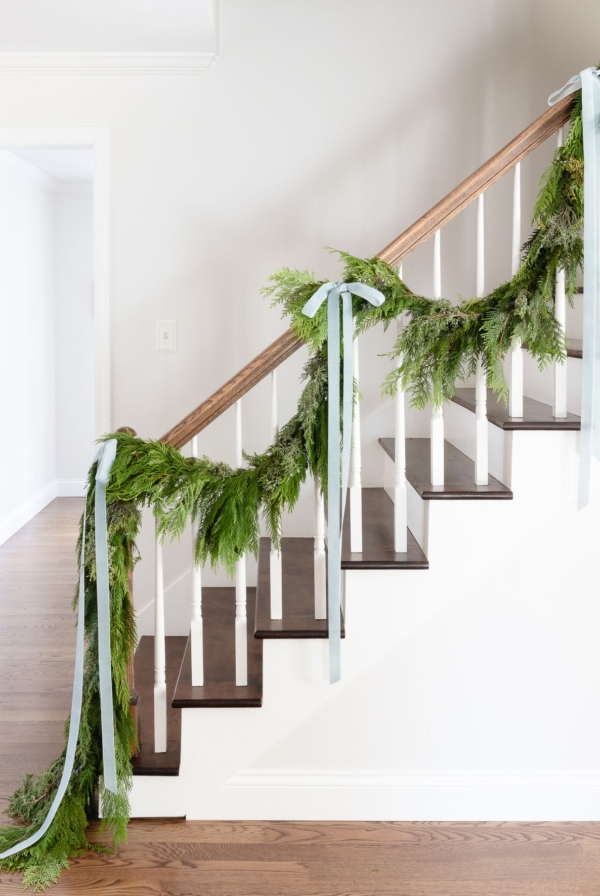 Fresh cedar garland on a staircase, tied with blue ribbon