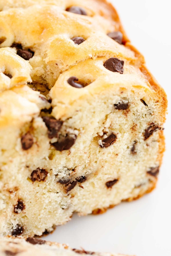 A chocolate chip bread loaf on a marble countertop, sliced for serving.