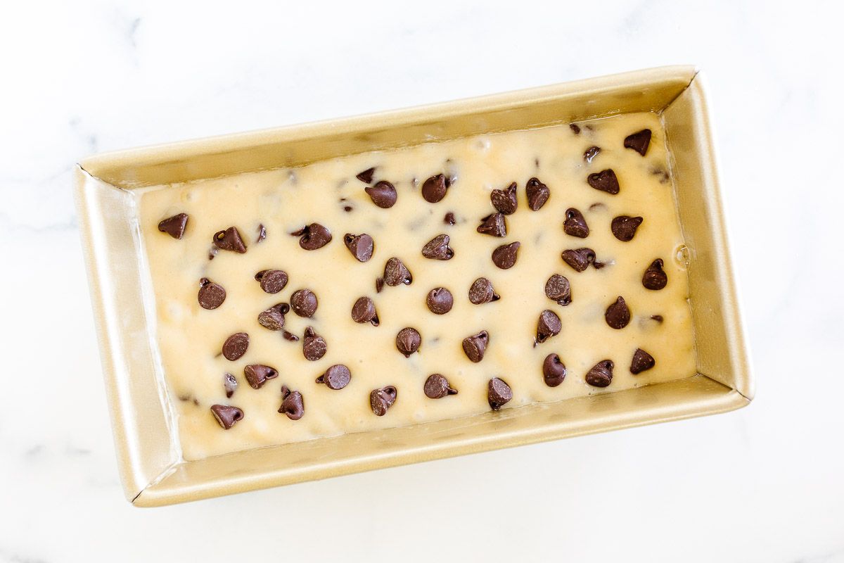 Chocolate chip loaf batter inside a gold loaf pan prior to baking.