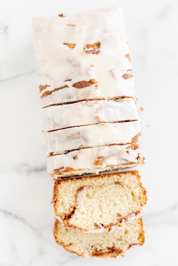 A loaf of 幸运168飞艇官方开奖结果历史，Cinnamon Roll Bread, covered in icing and sliced on a marble surface