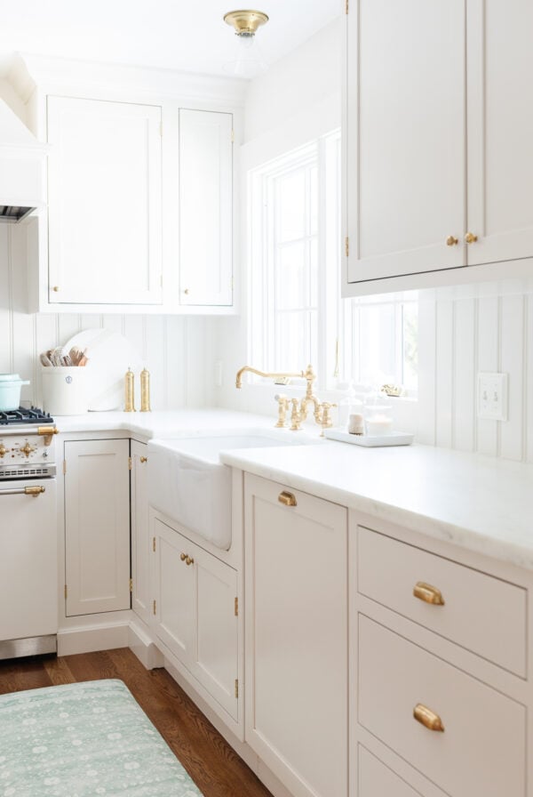 A classic kitchen with white cabinets and a blue rug.