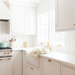 Cream kitchen cabinet with brass knobs in a traditional kitchen.