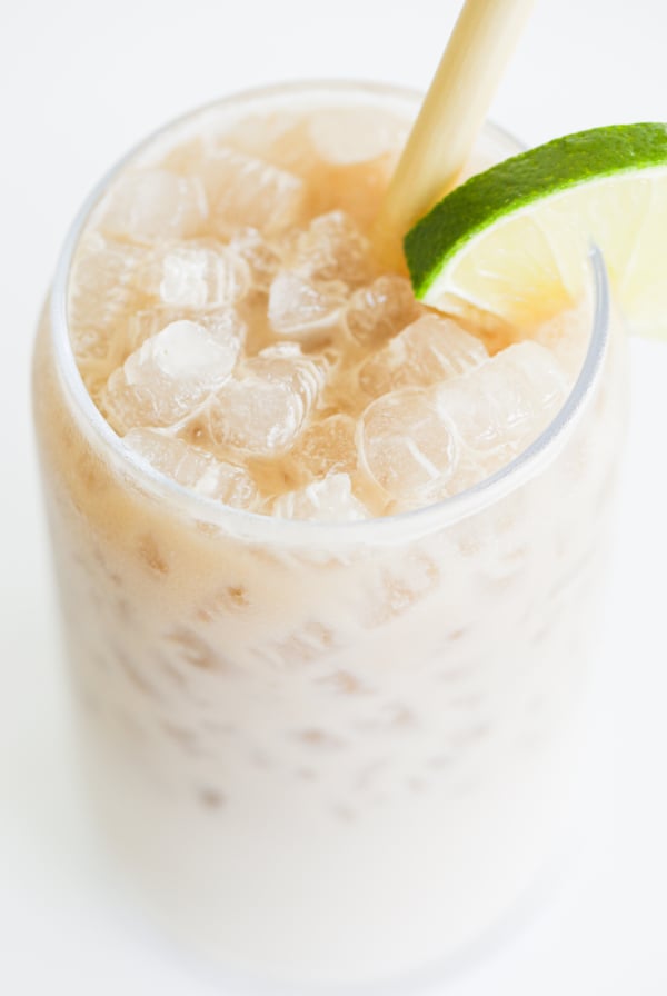 A close-up of an iced dirty Dr Pepper, garnished with a slice of lime on the rim, featuring a straw for sipping.