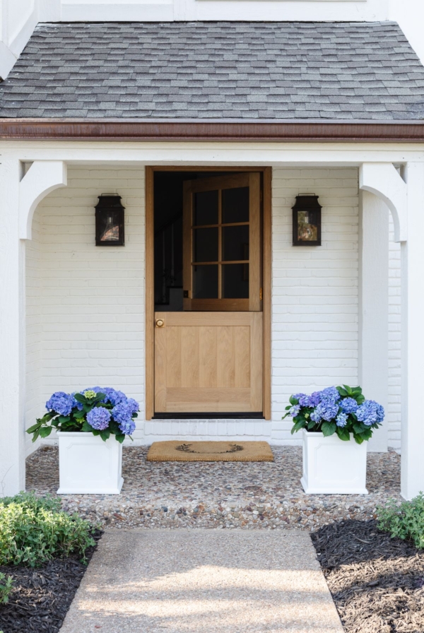 A wood Dutch door on a white brick home.