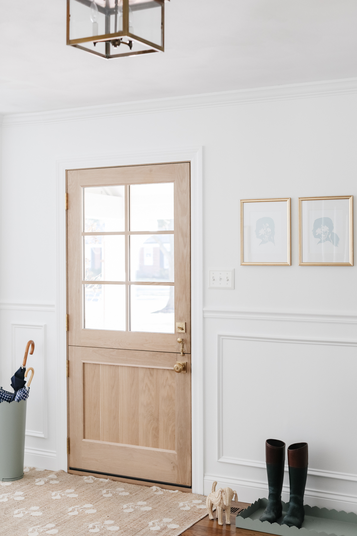 Foyer design: A white entryway with a wooden door and a rug.