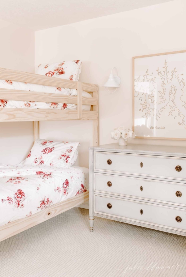 Girls bunk beds with floral bedding in a pink bedroom.