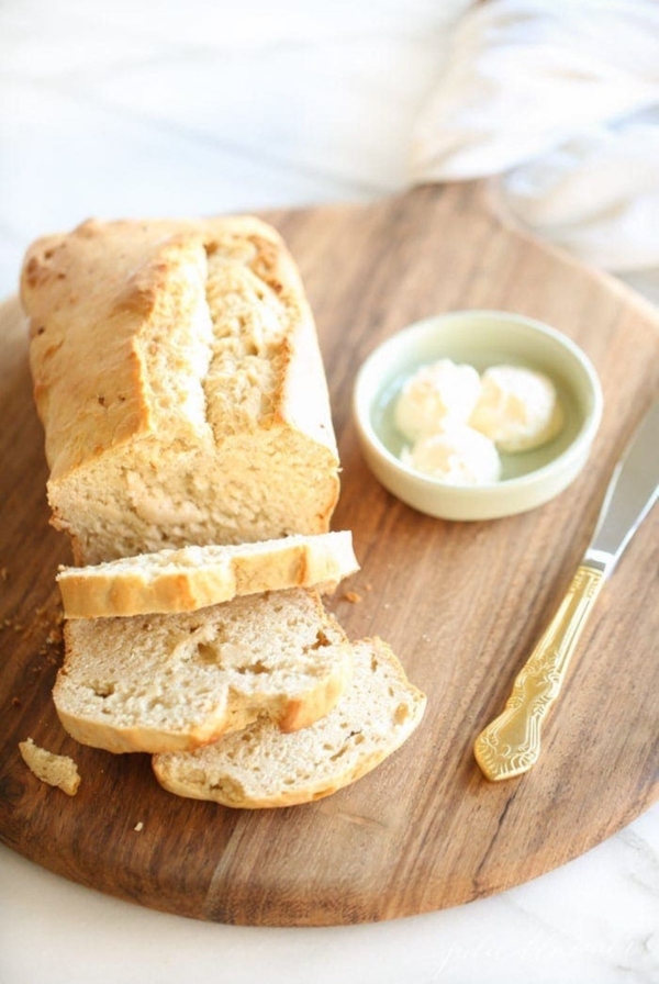 A slice of honey beer bread on a wooden cutting board.