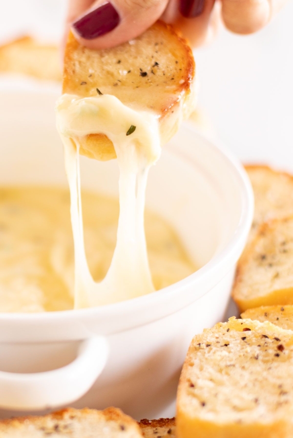 Hot garlic cheese dip stretching out of a white bowl