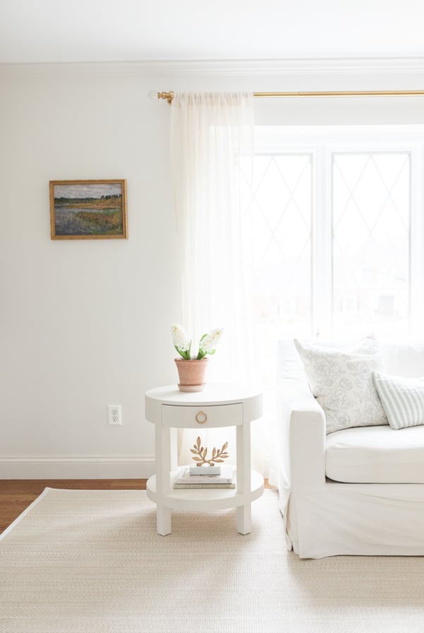 A white living room with white furniture and a soft beige rug.