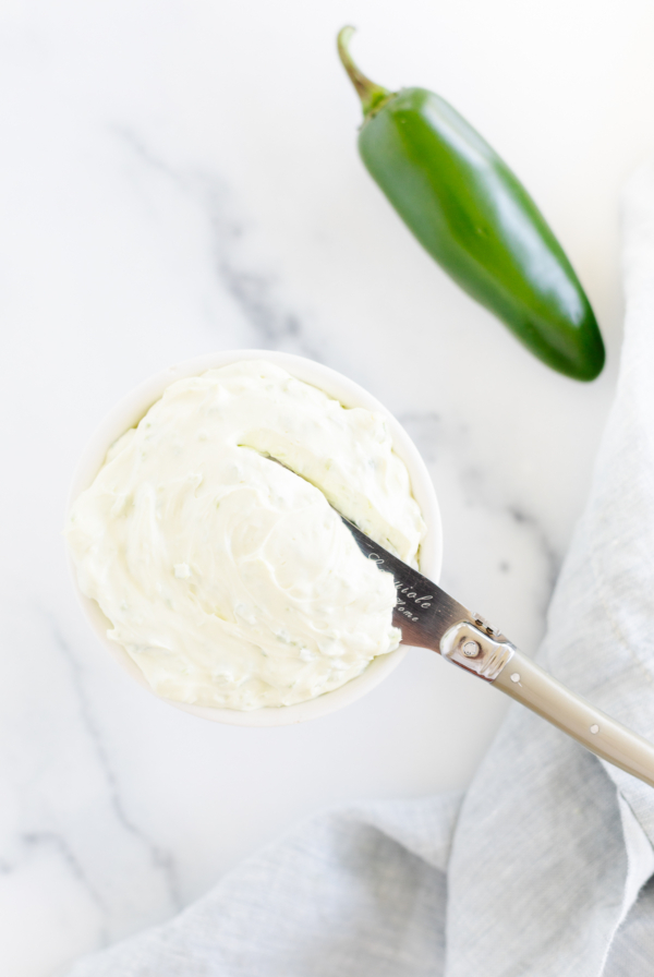 A bowl of cream with a jalapeno in it.