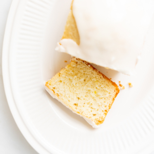 A sliced lemon cake with lemon glaze on a white oval plate.