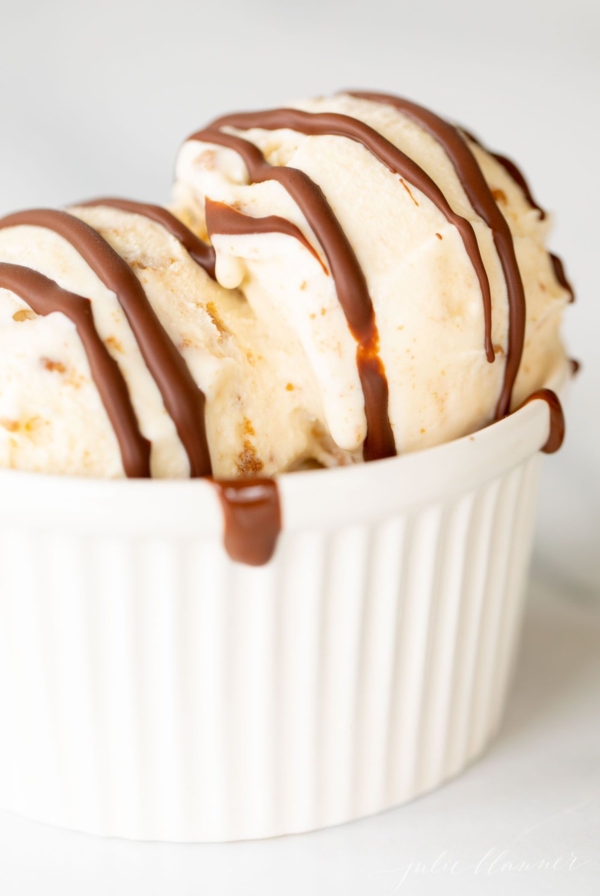 A white bowl of ice cream topped with chocolate magic shell.