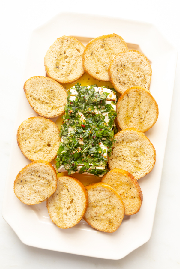 A plate with a piece of marinated cheese and bread on it.