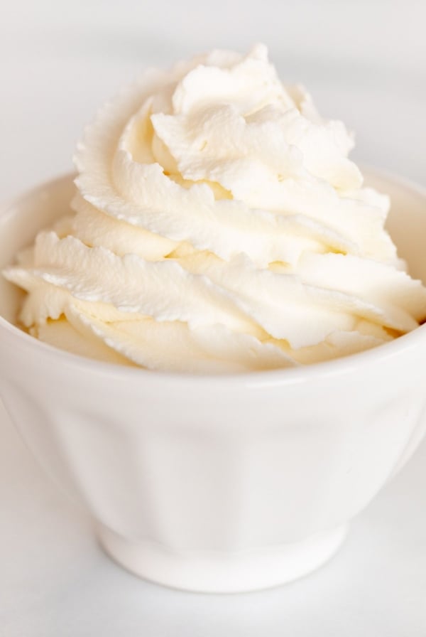 A white bowl full of whipped mascarpone cream on a marble surface.