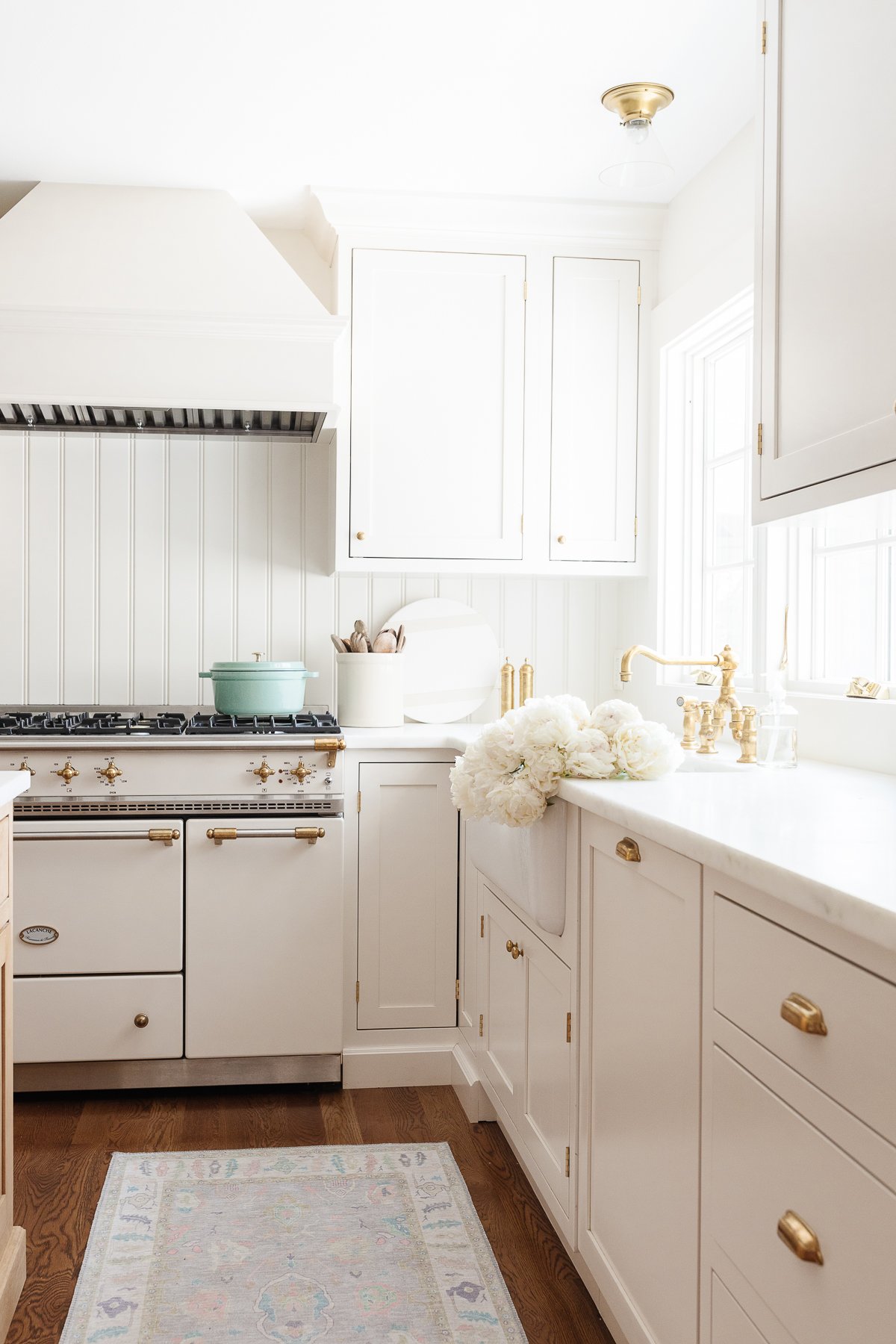 A minimalist kitchen with cream cabinets, marble countertops and a French range.