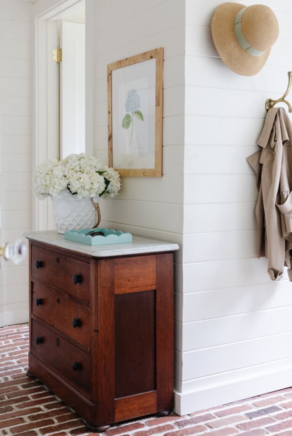 A mudroom with an antique chest and hydrangeas in a vase