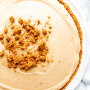 No bake cookie butter cheesecake in a white ceramic pie pan.