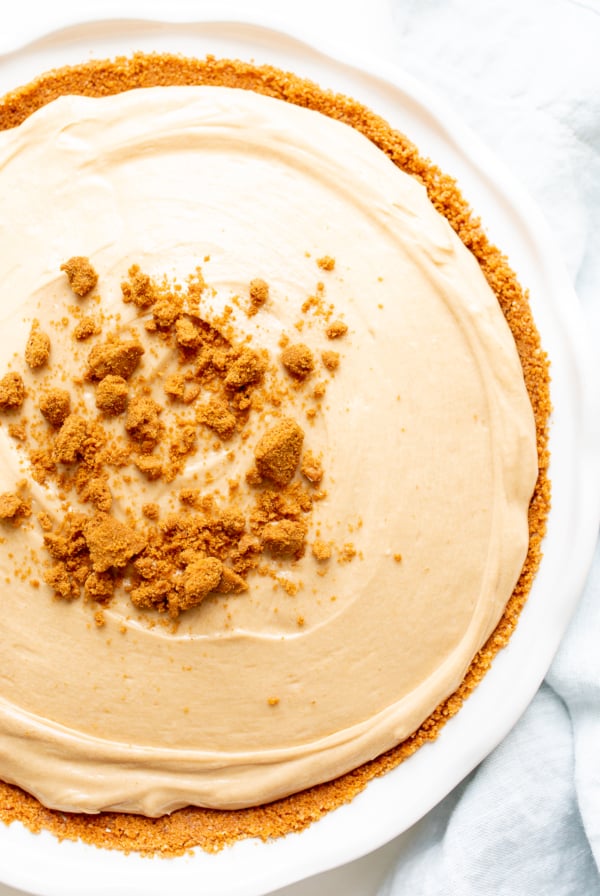 No bake cookie butter cheesecake in a white ceramic pie pan.