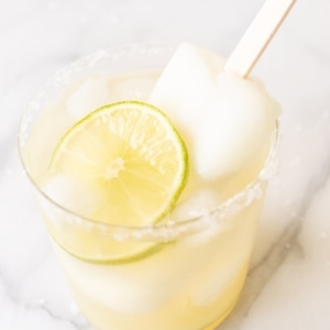 A Lime Popsicle Margarita in a glass on a marble surface.