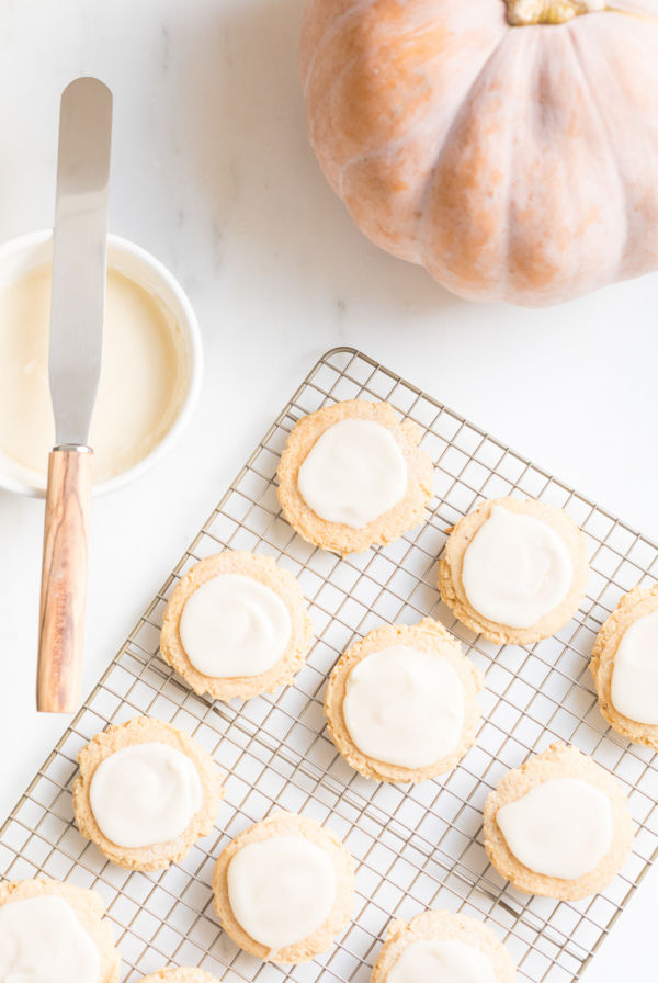 pumpkin sugar cookies with cream cheese glaze on a cooling rack