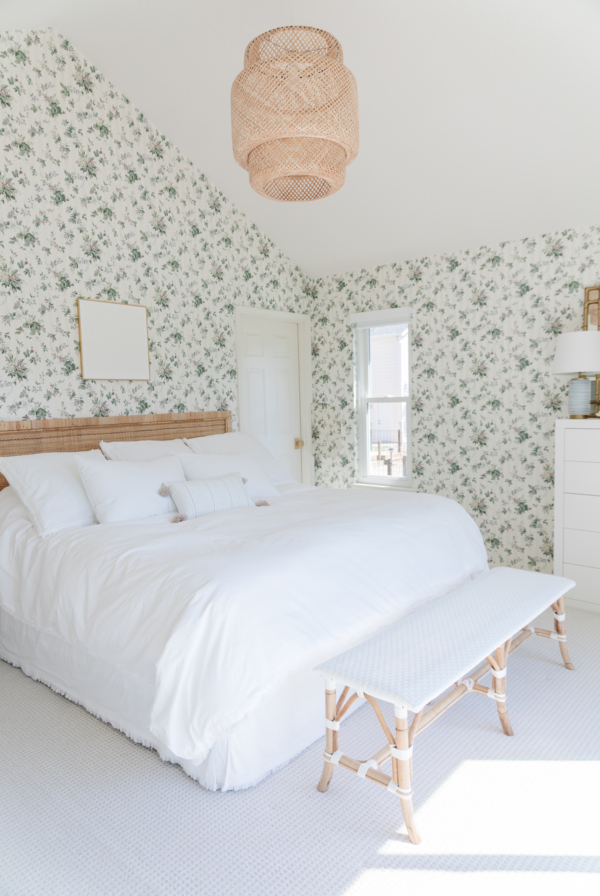 A Rattan Bed in a bedroom with floral wallpaper.