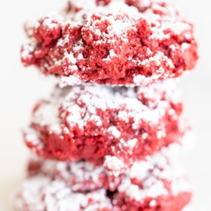 A stack of red velvet gooey butter cookies on a white surface.