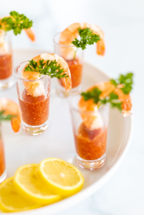 A platter of shot glasses filled with individual shrimp cocktails