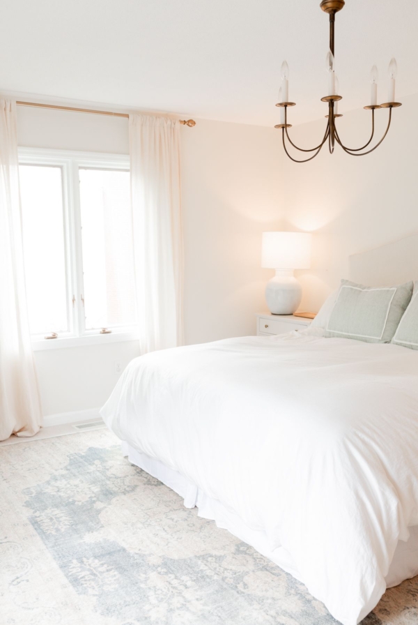 A white bedroom with a vintage rug on carpet