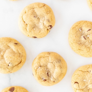 Salted caramel chocolate chip cookies on a parchment lined baking sheet.