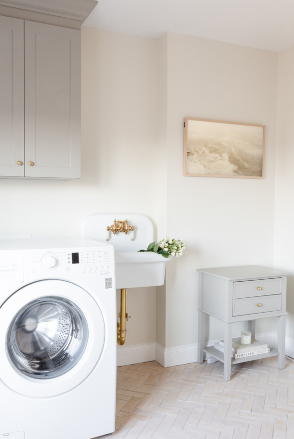 A second level laundry room with greige cabinetry and a wall sink