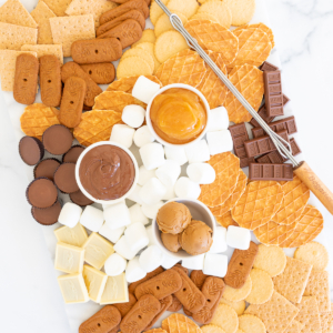 A s'mores charcuterie board filled with various marshmallows, cookies, crackers and dessert spreads.