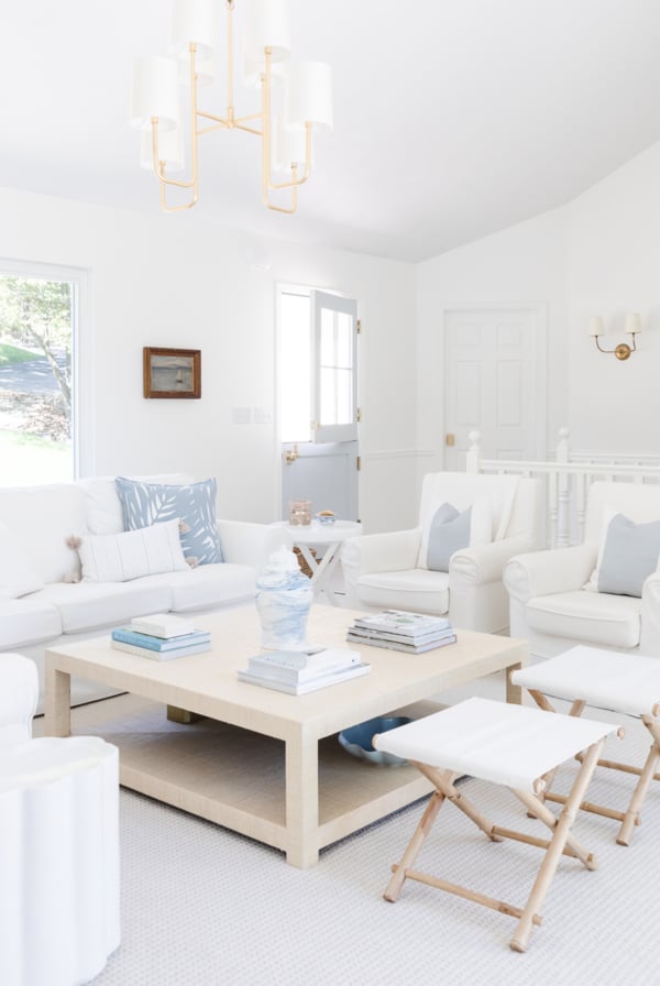 A white living room with white furniture and wall to wall carpet.