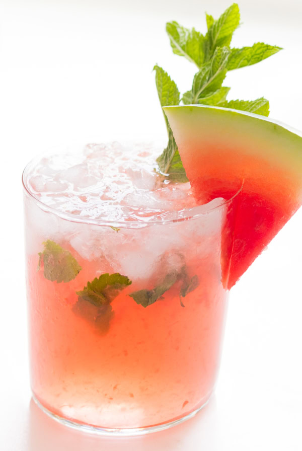 A refreshing watermelon mojito garnished with a slice of watermelon and fresh mint leaves in a clear glass.