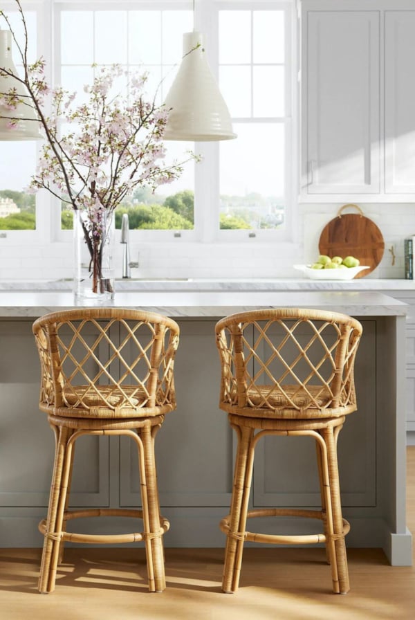 Two rattan bar stools grace the white kitchen.